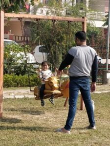 baby on swing with father in the park in winters
